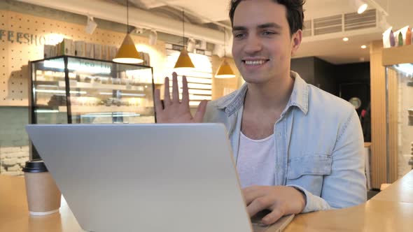 Video Chat in Cafe on Laptop By Young Man Talking with Customers