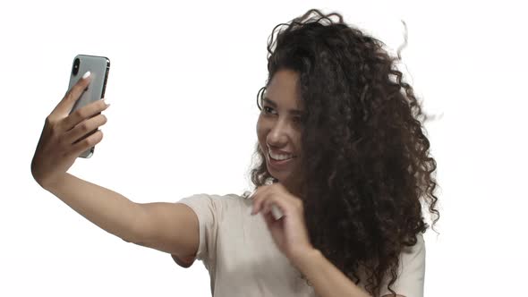 Closeup of Beautiful Mexican Girl with Long Curly Hairstyle Taking Selfie on Mobile Phone Standing