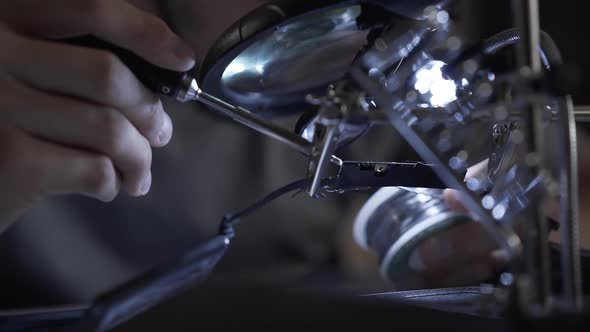 Unrecognized Successful Man in Glasses Working with a Soldering Iron at His Working Place