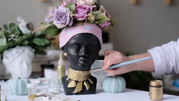 Woman Decorates a Vase in the Form of a Plaster Bust