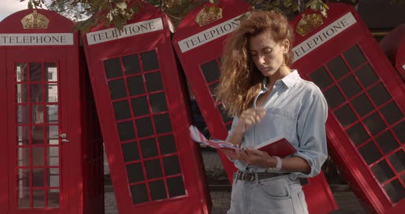 Attractive Girl Walking on a Background of Red British Phones. Travel, Tourist Places Concept