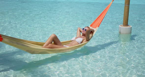 Relaxed Woman Lying on Hammock Over Pool