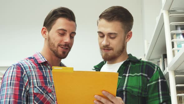 Two Guys Read Papers in a Folder and Laugh