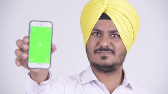 Face of Happy Bearded Indian Sikh Businessman Showing Phone