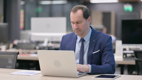 Businessman Having Headache While Working on Laptop