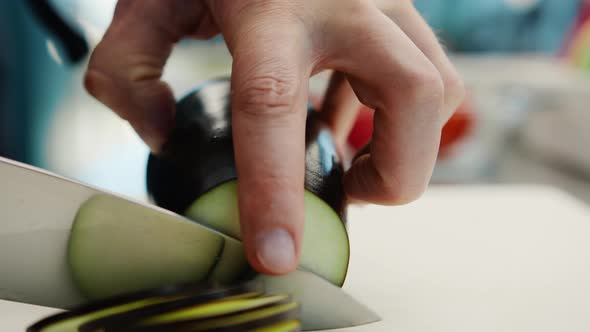 Close-up: A chef cuts an eggplant with fine pressure on a cutting surface in a professional kitchen