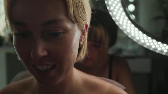 A Closeup of a Woman's Face Smiling and Surprised From the Pain While Doing a Tattoo