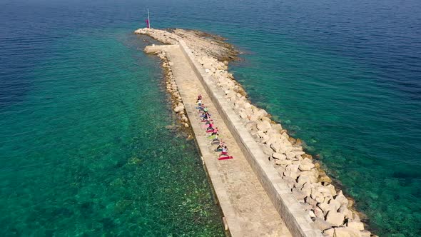 Aerial view of group practicing yoga at artificial pier, Veli Losinj, Croatia.