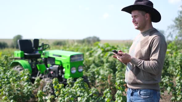 A Village Worker Speaks on the Phone Next to His Tractor