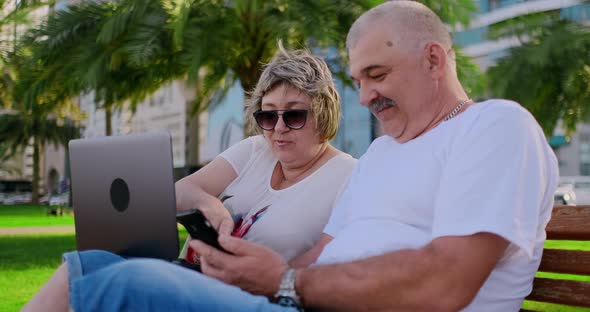 Senior Couple Using a Laptop in a Park on a Sunny Day