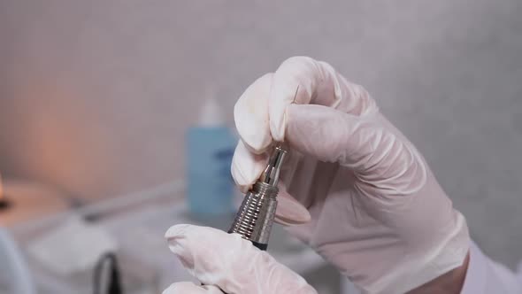 Closeup Gloved Hands Insert a Needle Into a Machine for Permanent Makeup