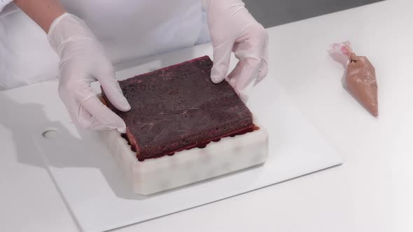 Pastry Chef Puts the Chocolate Biscuit Into a Silicone Mold with Chocolate Mousse