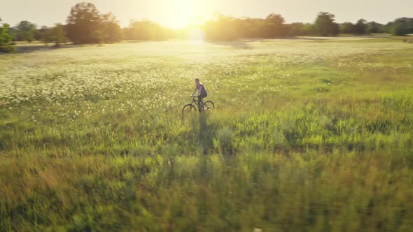 Woman Ride Bike at Sun Field Aerial