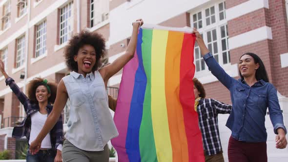 Happy diverse group of men and women holding rainbow flag during protest