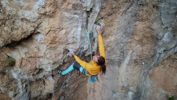 Aerial Slow Motion Skilful Athletic Male Rock Climber Climbs on Overhanging Rock Cliff