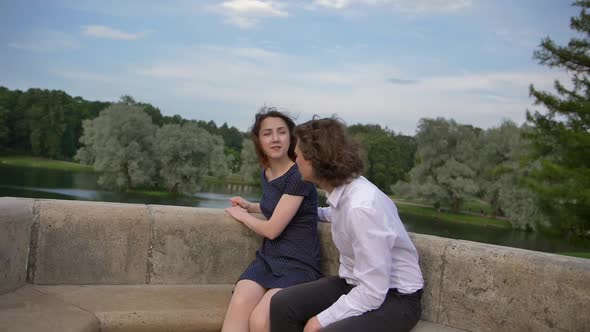 Two Young People in Love Are Hugging on a Stone Bench.