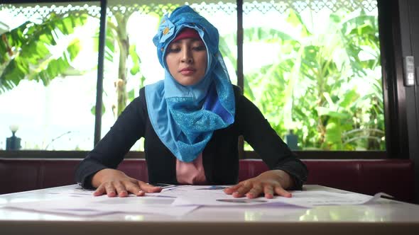 Portrait of unhappy Arab woman working with documents