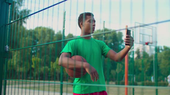 Streetball Player with Phone Live Streaming on Court