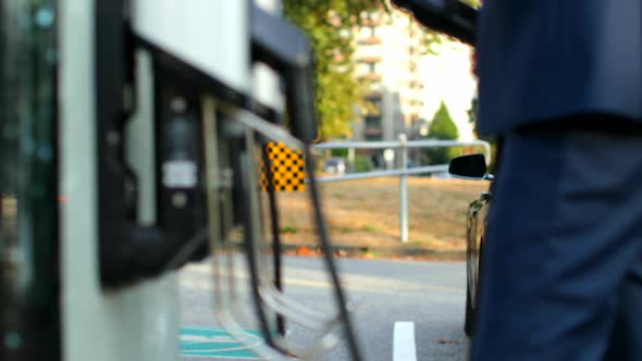 Businessman charging electric car at charging station 4k