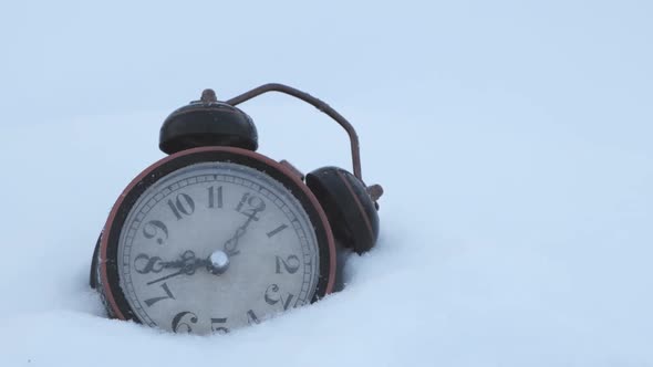 An old alarm clock rings at eight in the morning after falling in the snow.