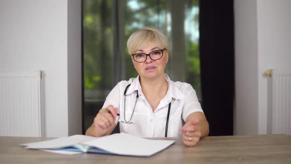 The Serious Women Physician in Glasses is Listening the Symptoms of Patient