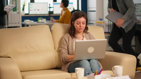 Young Woman Entrepreneur Sitting on Couch Looking at Camera