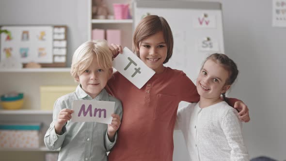 Happy Kids with Letter Flashcards in Classroom