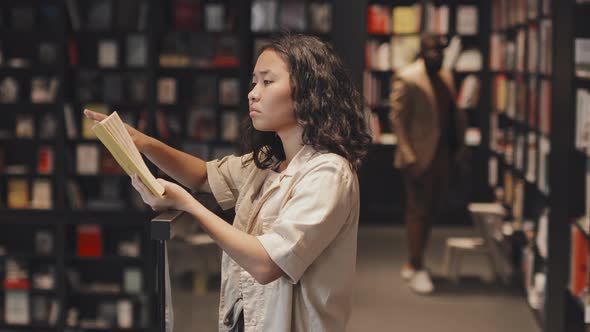 Female Asian Student Reading Book in Modern Library