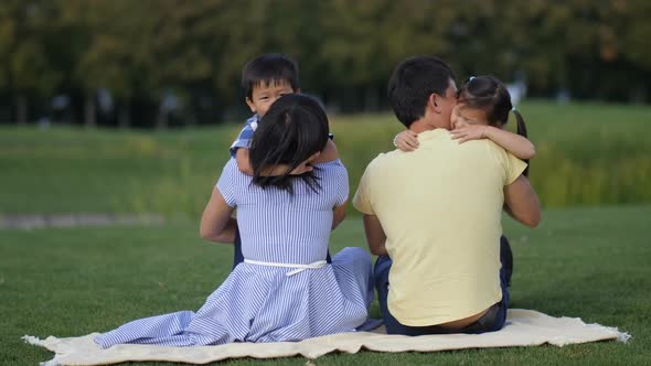 Cute Asian Kids Tenderly Embracing Parents in Park alt