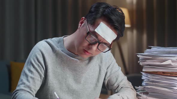 Close Up Of Sick Asian Man Working Hard With Documents At The Home