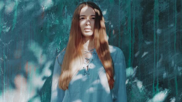 young beautiful woman with shadows on face with long red hair and blue shirt