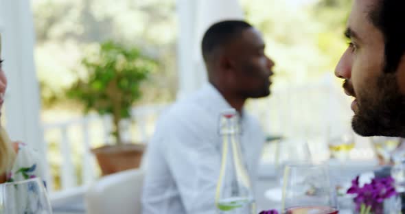 Friends interacting with each other while having glass of wine