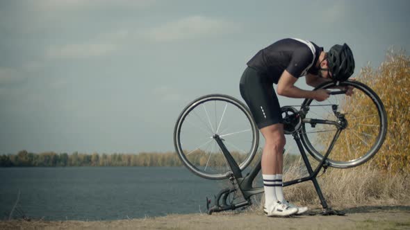 Cyclist Checking His Bike After Triathlon. Triathlete Fixes His Bicycle After Breakdown. Bicyclist.