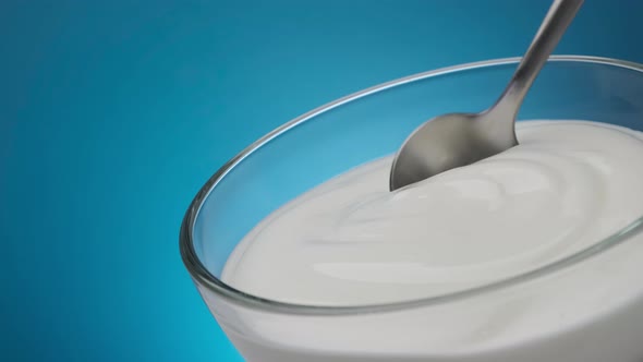 Bowl of sour cream on blue background, greek yogurt