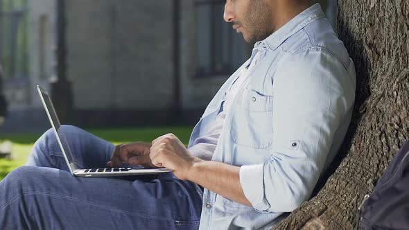 Male Freelancer Working on New Project Snugly Locating in Shadow of Wide Tree