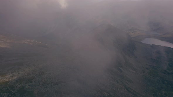 Flying through the clouds as a large mountain is revealed.