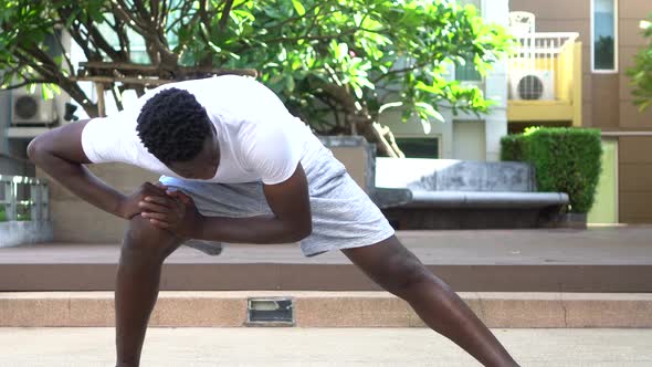 Athletic African American Man in Doing Stretching Exercise While Training in Park on Sunny Day