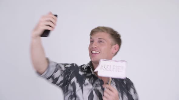 Happy Young Handsome Tourist Man Taking Selfie with Paper Sign