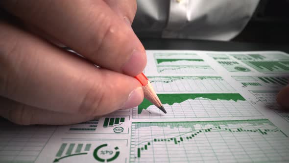 Accountant analyzing business marketing data on paper dashboard at office table.