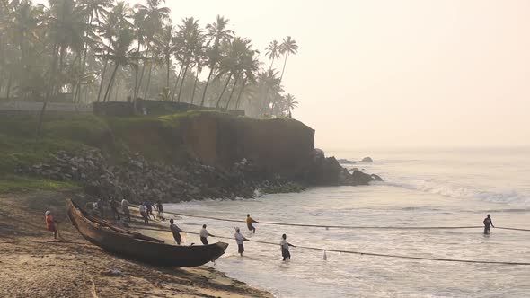 Local people working with traditional fishing nets, Kappil Beach, Varkala, India, at dusk