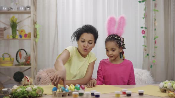 Mom and Daughter with Funny Bunny Ears Consider at Painted Eggs