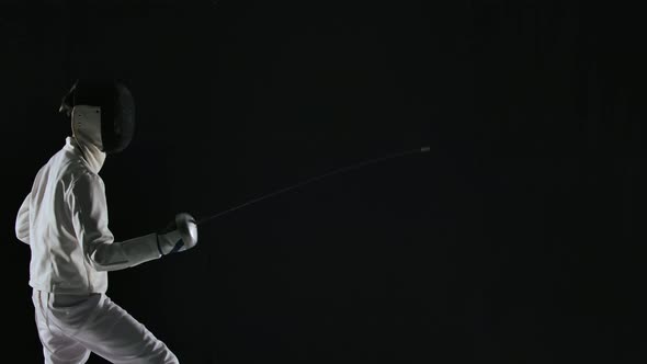 Side View of Young Boy in White Uniform and Mask Masterfully Wields Rapier on Black Studio