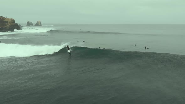 Aerial shot following Surfer riding Wave and falling on a cold day at Pichilemu, Chile