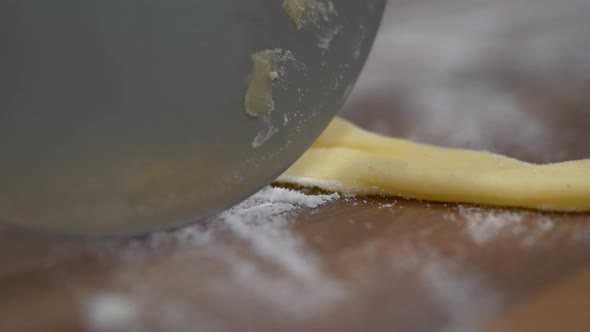 Pizza Cutter Rolling And Cutting Faworki Dough With Flour. extreme close up, slow motion