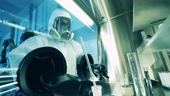 A Specialist is Working with Test Tubes Inside of a Vacuum Cabinet