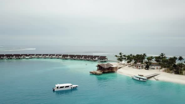 Drone shot, Maldives island, port side, water villas and yachts, blue lagoon and a mini jungle. 4K