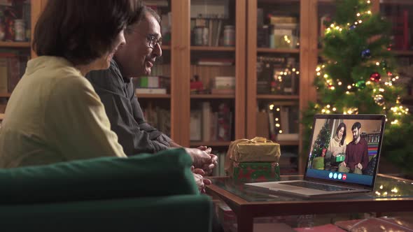 Happy family celebrating 2021 online Christmas with laptop and video call