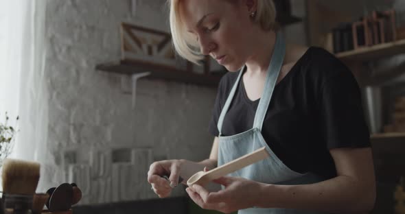 Woman Carpenter Polishes Wooden Spoon with a Sandpaper Close-up