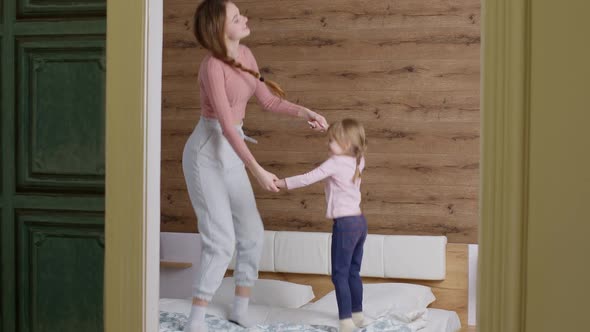Happy Funny Family Mother and Child Kid Daughter Dancing Jumping on Bed Listening Music at Home