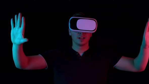 Young Man in VR Glasses. A Man Immersed in Virtual Reality Makes Movements with His Hands. Blue and